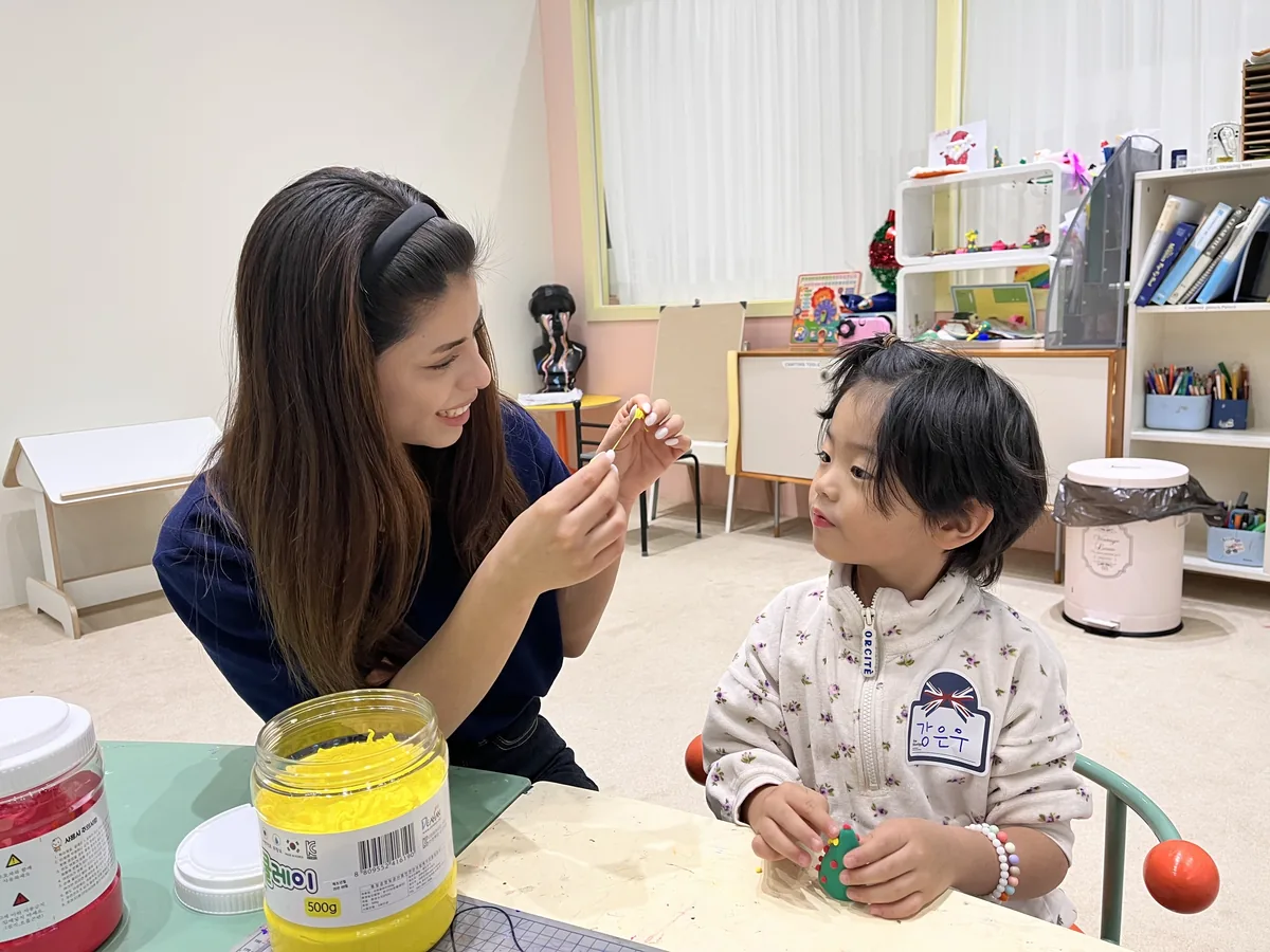 원어민 선생님이 만든 점토를 들어 보이자 올려다보는 아이